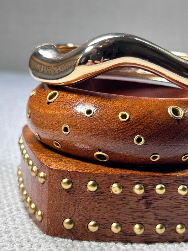 Close-up of Khanak Avira wooden bangle stack with gold studs and wavy stainless steel bracelet.